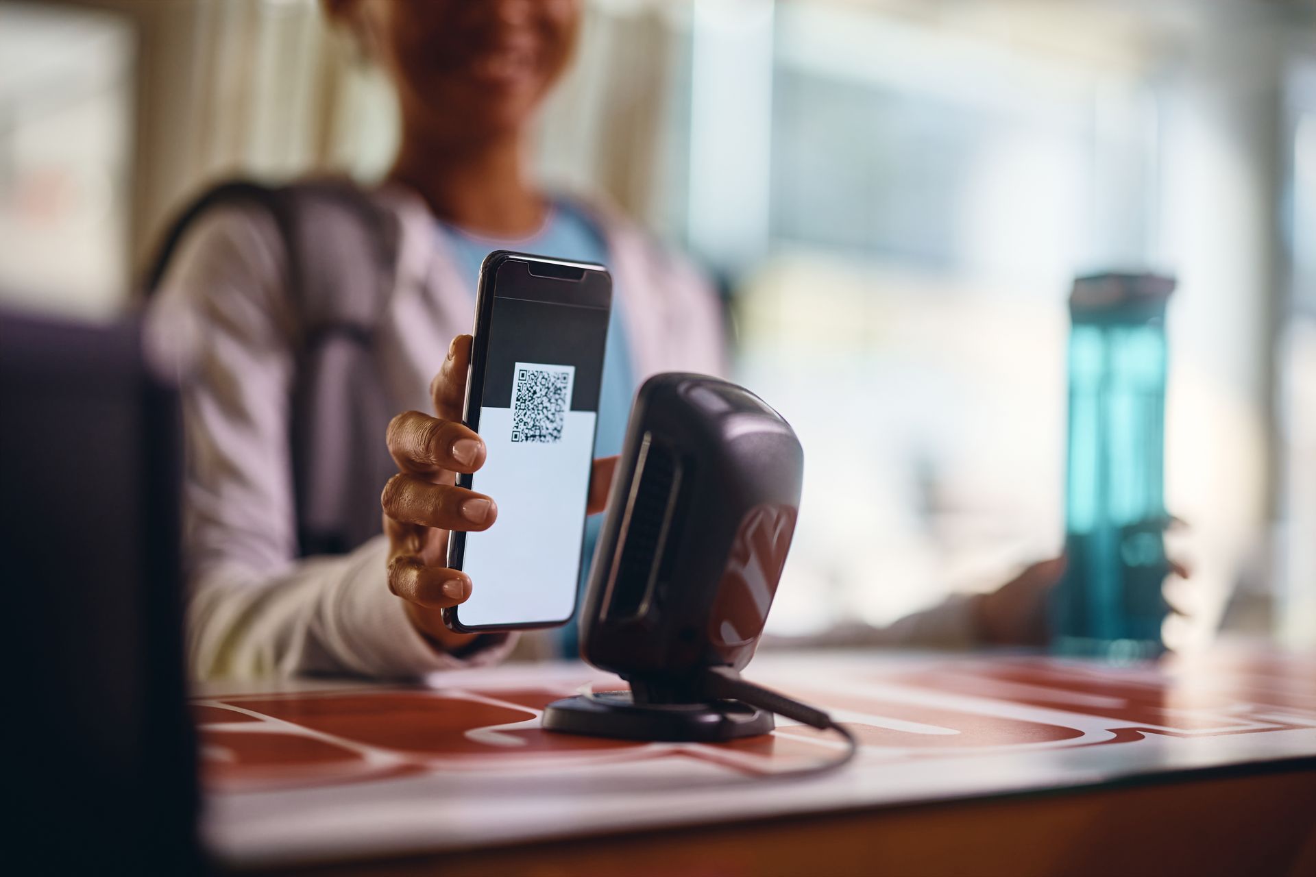A customer presents a QR code on a phone at a counter scanner.