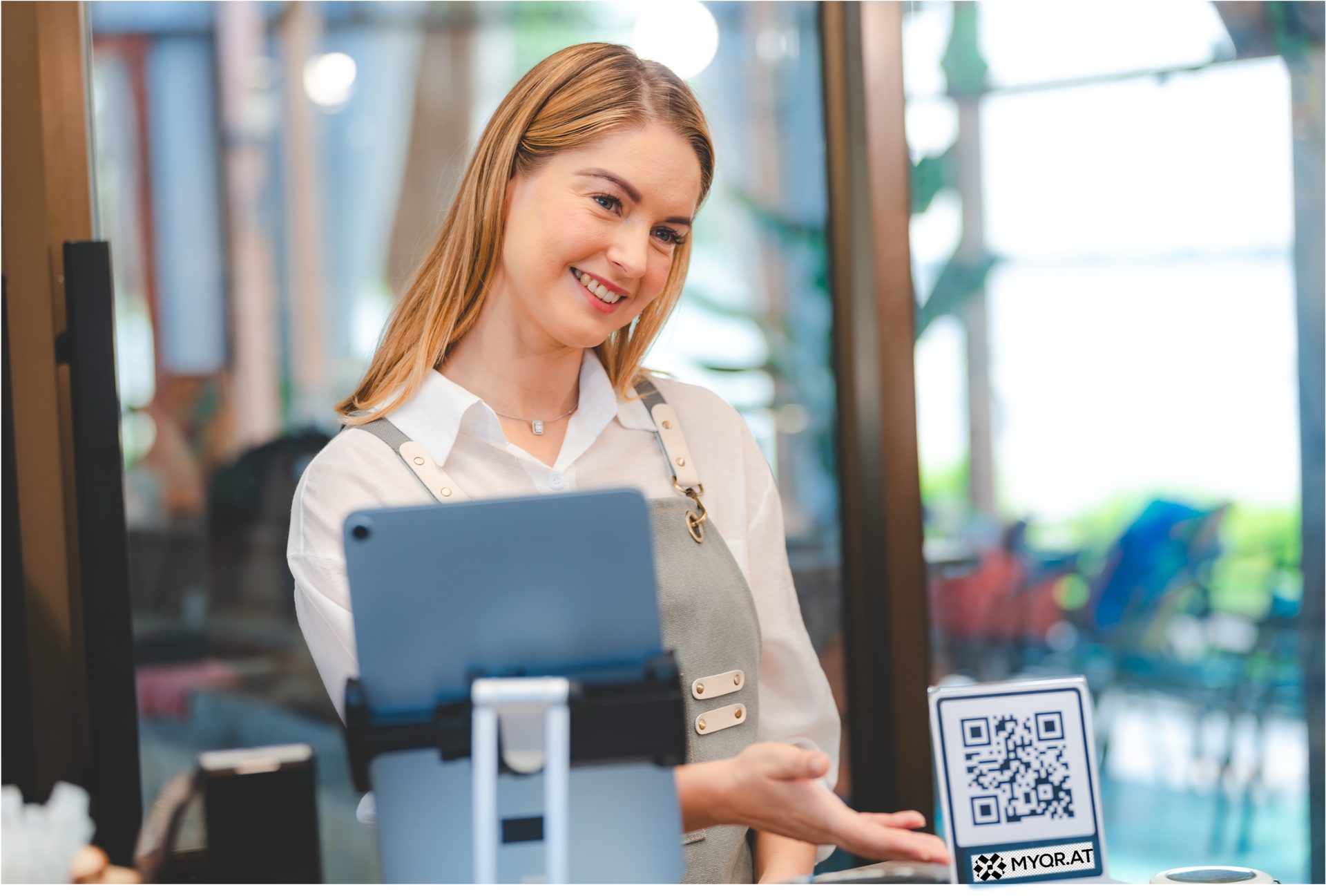 A café attendant presents a MYQR scan-to-pay code at the counter.
